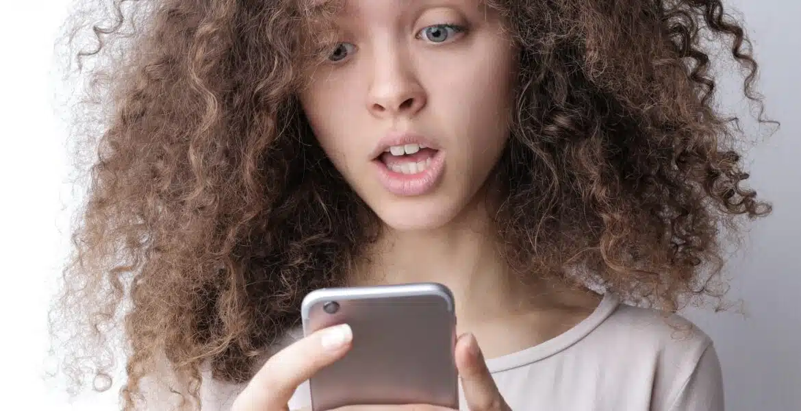 Surprised young woman browsing mobile phone
